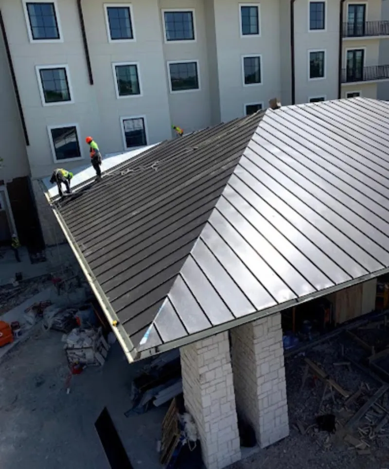 Crew installing standing seam metal roof panels on a commercial project in Bradford